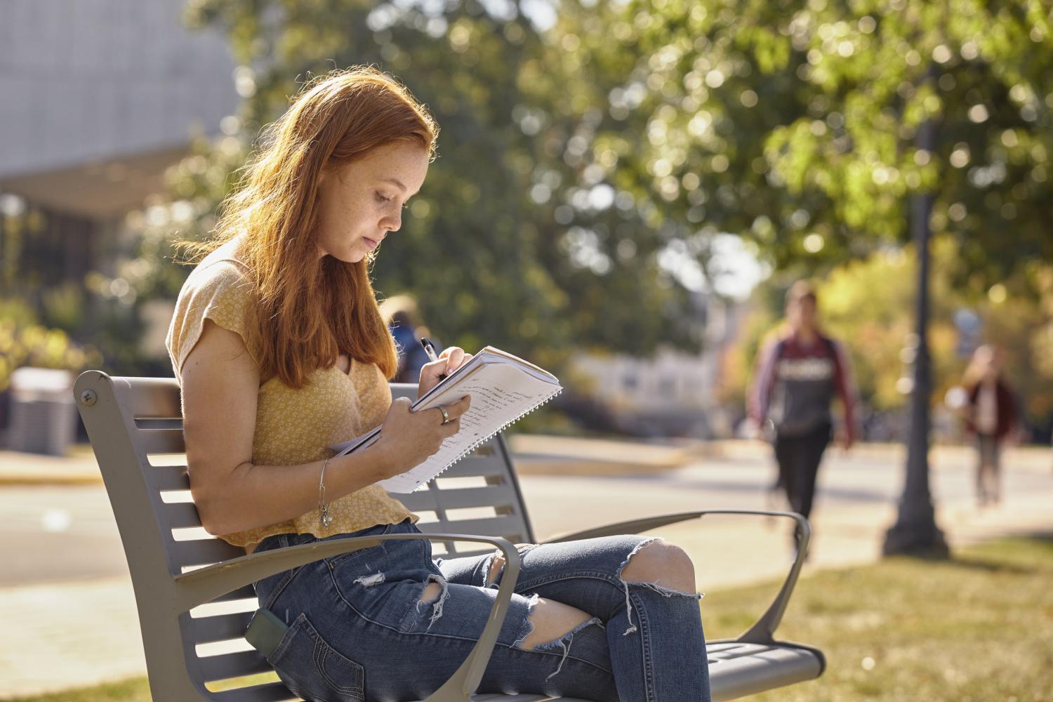 一位<a href='http://ptyh.litpliant.net'>全球十大赌钱排行app</a>学院的学生在校园里的长椅上读书.